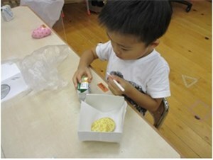 自分で作った紙皿にペーパーシートを敷いてクッキーを配膳してもらった男の子の画像