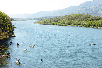 穏やかな流れの吉野川に数隻の筏やボートが浮かんでいる写真