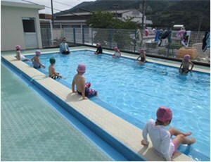 穴吹小学校のプールでプールサイドに座り先生の話を聞く子供達の様子