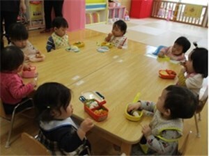 教室で椅子に座ってお弁当を食べる園児たちの写真