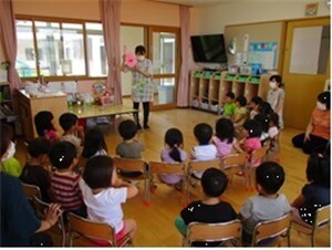 教室で椅子に座って先生から歯の磨き方を教わる園児たちの様子