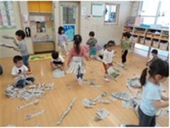 教室で新聞紙を破ったり丸めたりして遊ぶ園児たちの様子