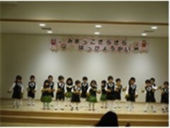 黒っぽい衣装を着てステージに立っている子供たち