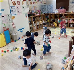 たくさんのボールが転がっている教室で遊ぶ園児たちの様子