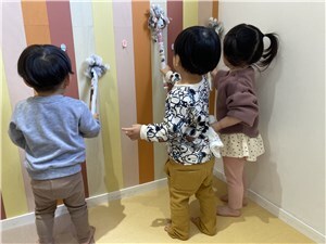 壁にはたきをかけている子供たちの写真